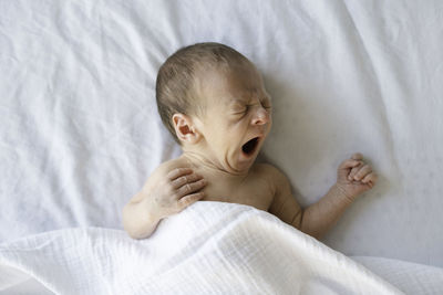 Close-up of cute newt baby boy sleeping yawning on bed at home