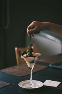 Midsection of person pouring wineglass on table