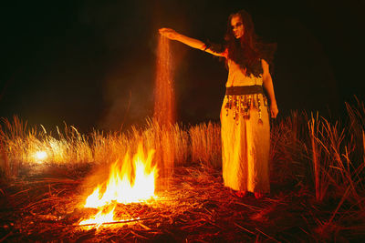 Woman standing by fire crackers at night