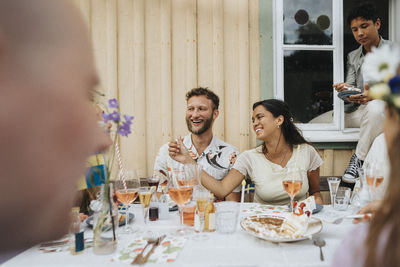 Man and woman enjoying with friends during dinner party while sitting at cafe table