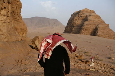 Rear view of man wearing traditional clothing in desert