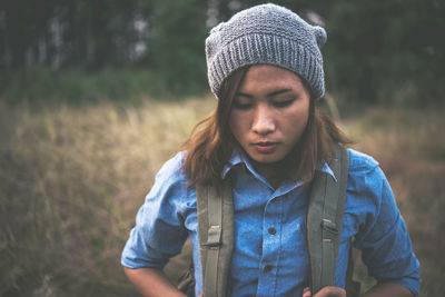 Close-up of thoughtful young woman wearing knit hat on field