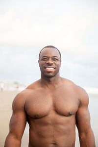 Handsome black man smiling. standing on the beach closed to ocean, half naked. vacation concept.