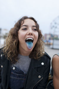 Young woman sticking out her blue tongue