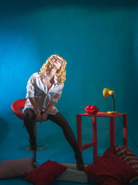 Fashion model with eyes closed sitting on chair in studio