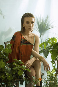 Portrait of young woman sitting on chair against wall