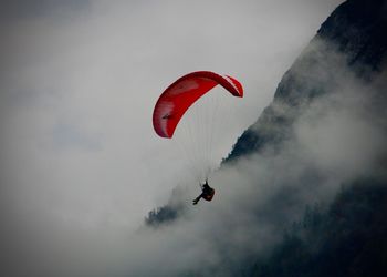 Low angle view of person paragliding against sky