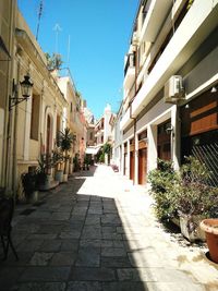 Sidewalk amidst plants in city against sky