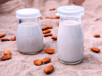 Close-up of milk bottles and almonds on jute