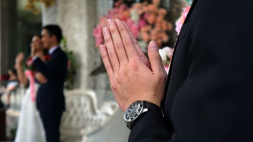 Midsection of man and woman standing against blurred background