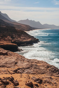 Scenic view of sea by rock formation against sky