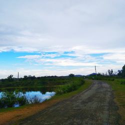 Road amidst field against sky