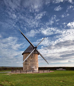 Traditional windmill on field against sky