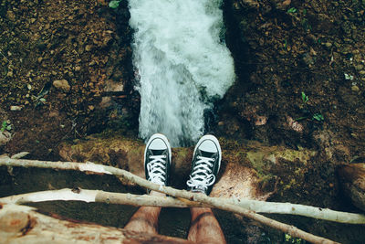 Low section of person standing by waterfall