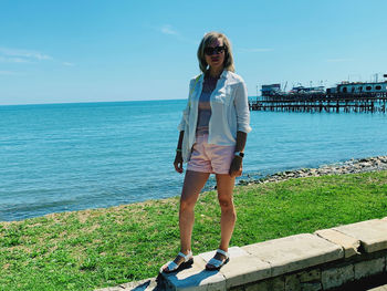 A girl of 30-35 years of european appearance in light clothes near the blue sea