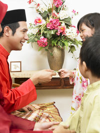 Father giving envelope to daughter at home