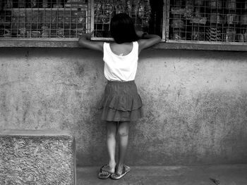 Rear view of girl standing next to shop window