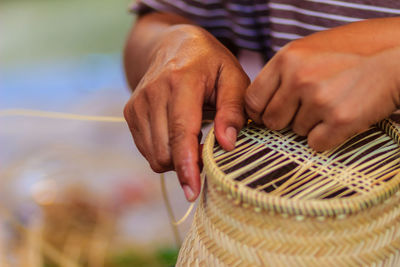 Midsection of man making wicker decoration