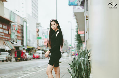 Full length portrait of woman standing against wall