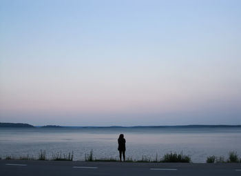 Silhouette of woman standing at water's edge