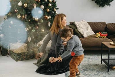 Mother with child playing near christmas tree. child and woman enjoy christmas mood christmas tree