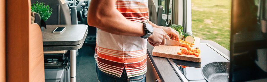 Unrecognizable man cooking vegetables in camper van