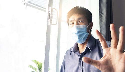 Portrait of man wearing mask sitting against window