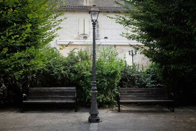 Gas light amidst empty benches against building