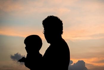 Silhouette father and son against sky during sunset