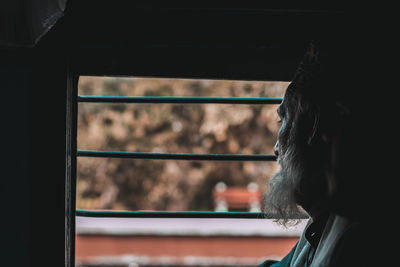 Close-up of man looking through window of train