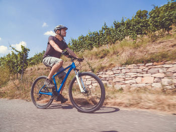 Man riding bicycle on street against sky