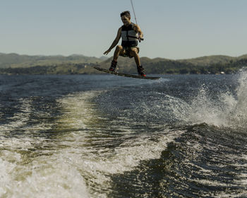 Full length of man surfing in sea against sky