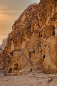 Bedouin sitting on carpet near a stairs carved on rocks in archaeological site ol little petra