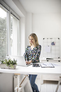 Young woman using phone while sitting on table