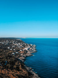 Aerial view of townscape by sea against clear blue sky