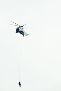 Low angle view of army soldiers hanging on rope attached to helicopter for rescue mission