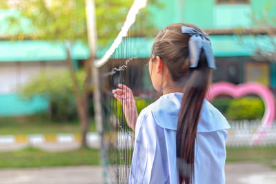 Rear view of woman standing by net