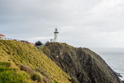 Lighthouse amidst sea and buildings against sky