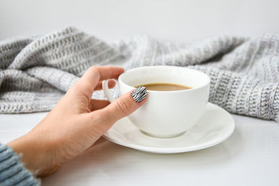 Hand in sweater with zebra animal printed nails with cup of coffee. female 
