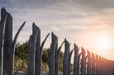 Low angle view of fence against sky during sunset