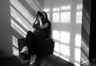 Woman photographing with camera while sitting at home