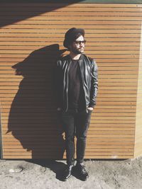 Portrait of young man standing against brick wall