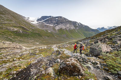 Rear view of friends hiking at mountains