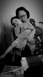 Rear view of mother and daughter sitting on floor