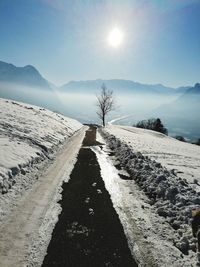 Scenic view of snow covered road against sky