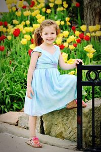 Portrait of smiling cute girl standing against flowering plants