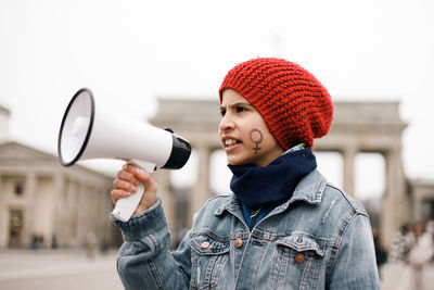 Teenage girl with a woman symbol painted on her face with a megaphone in her hand at a demonstration