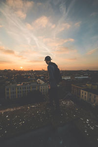 Man standing in city against sky during sunset