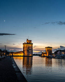 The old harbor of la rochelle at night with its famous old towers. moon in the sky. portrait format