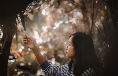 Portrait of young woman holding tree